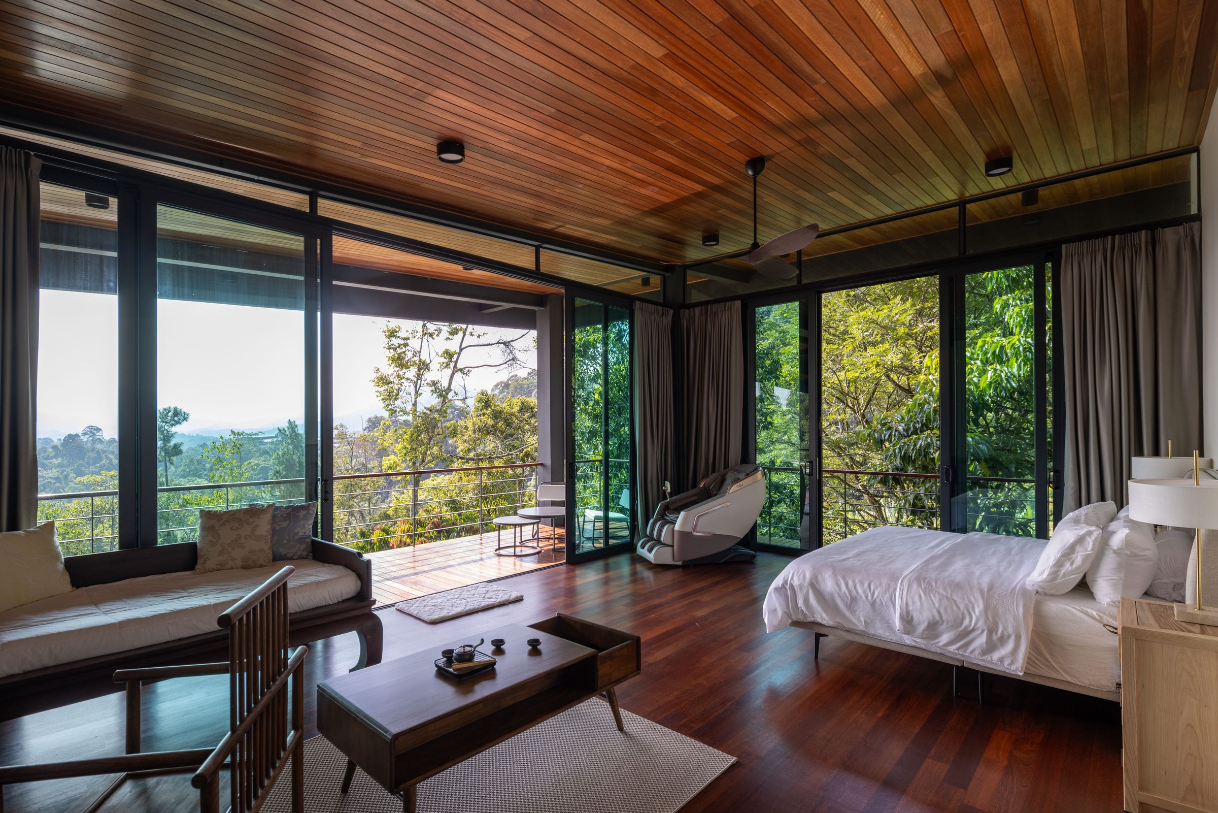 Bedroom suite at SereneNest with timber ceiling, floor-to-ceiling glass and a sitting area