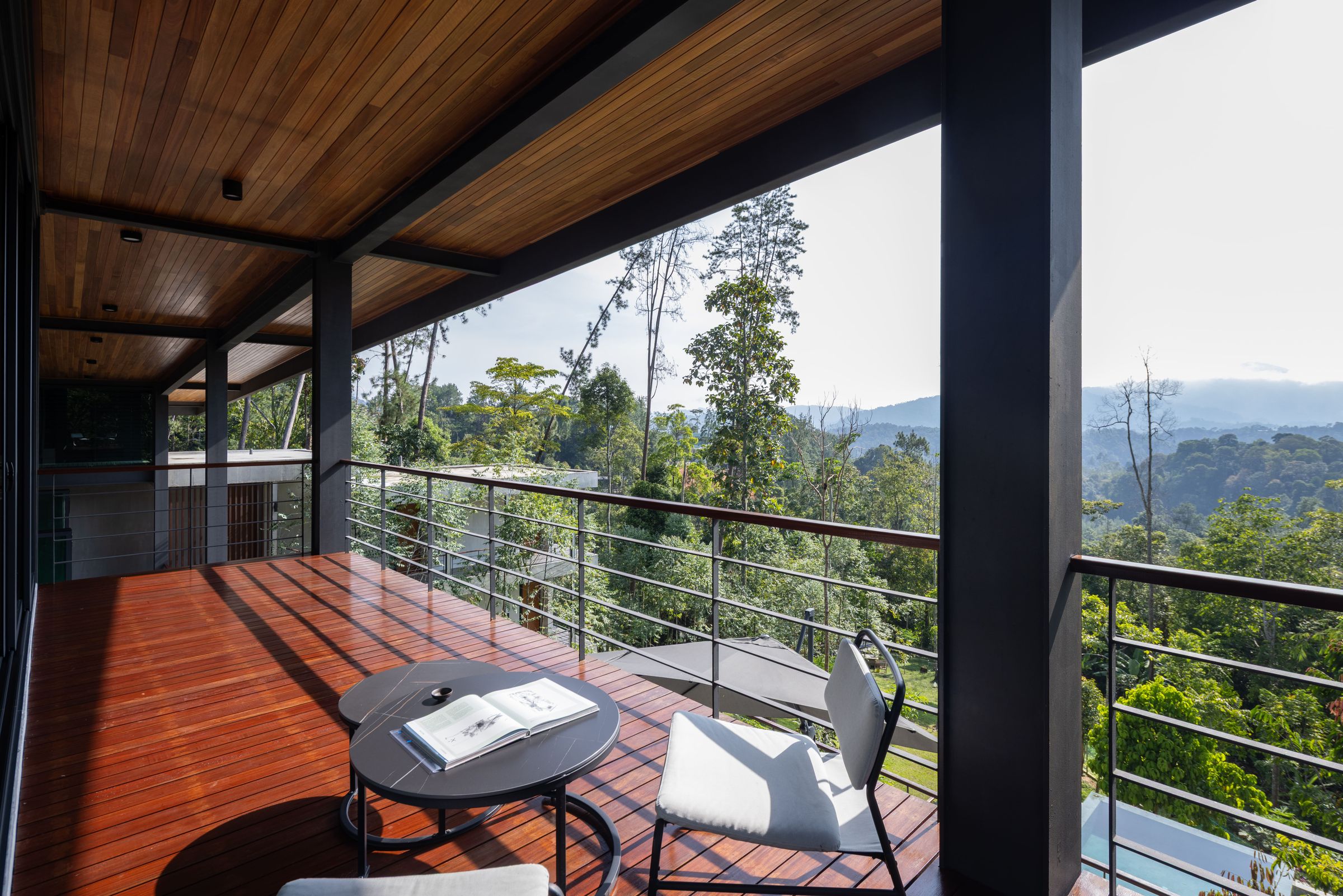 Quiet balcony chair and side table at SereneNest with a forested mountain view