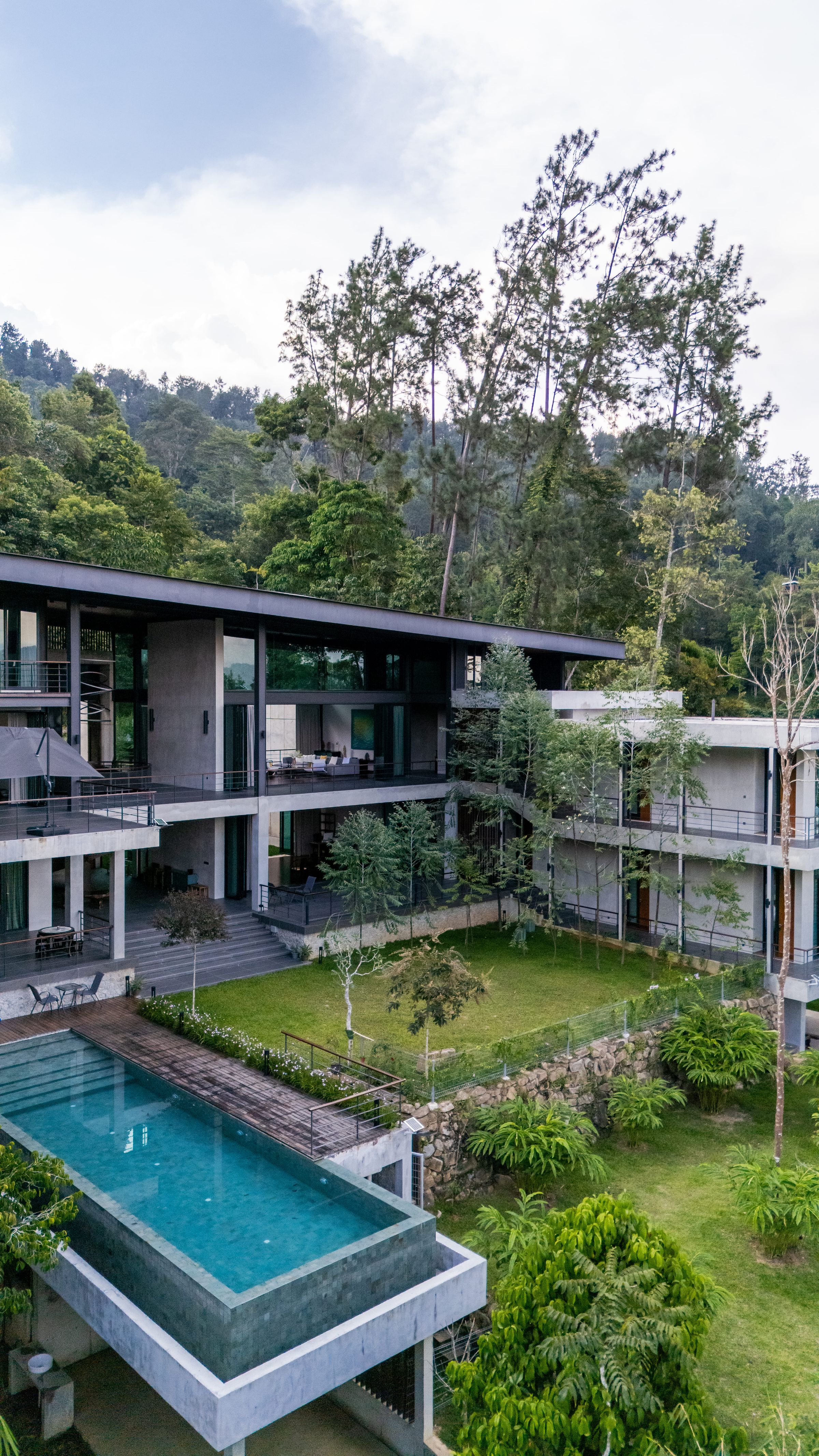 Elevated view of the SereneNest villa, infinity pool and surrounding rainforest