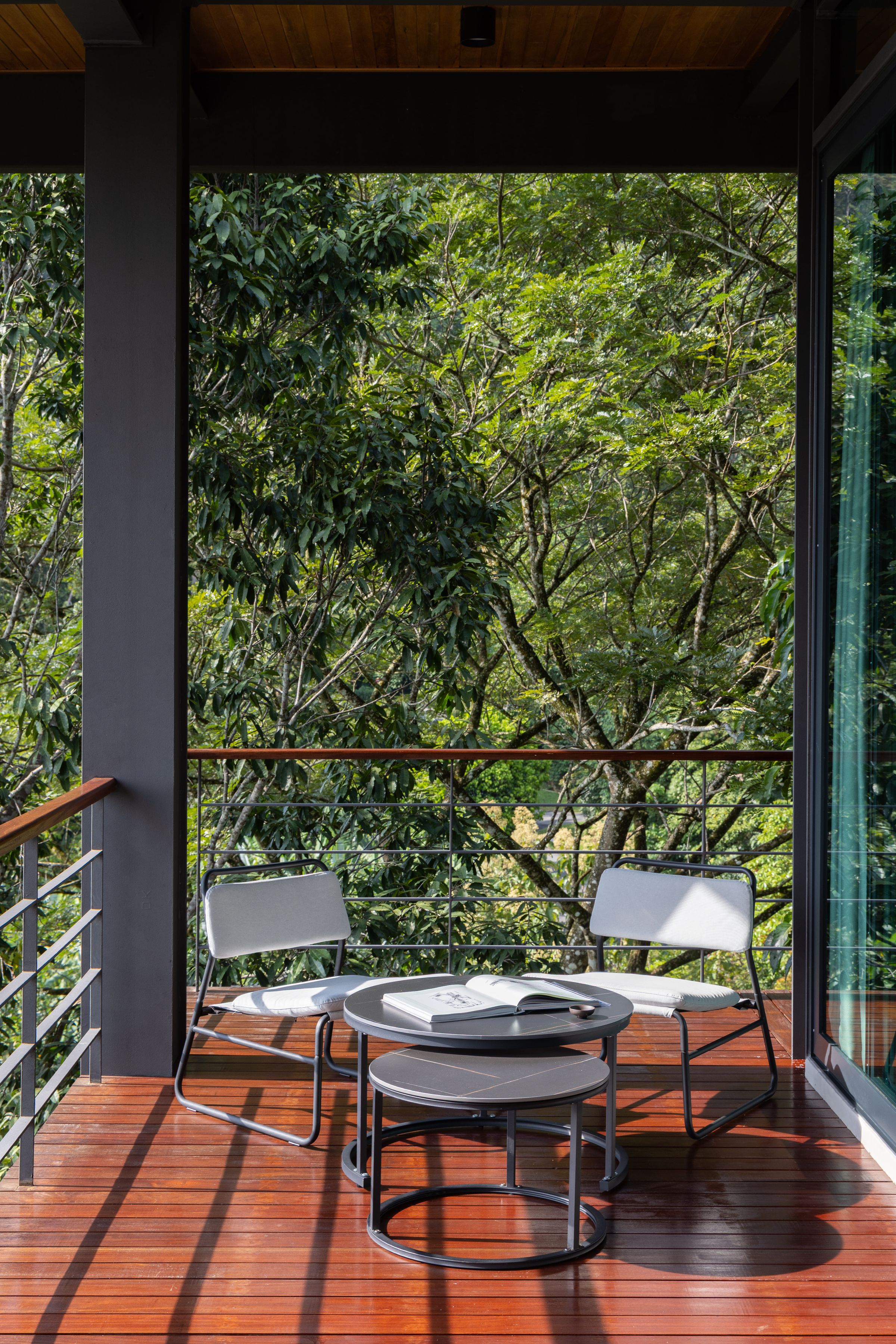 Balcony seating at SereneNest with a glass railing overlooking the rainforest canopy