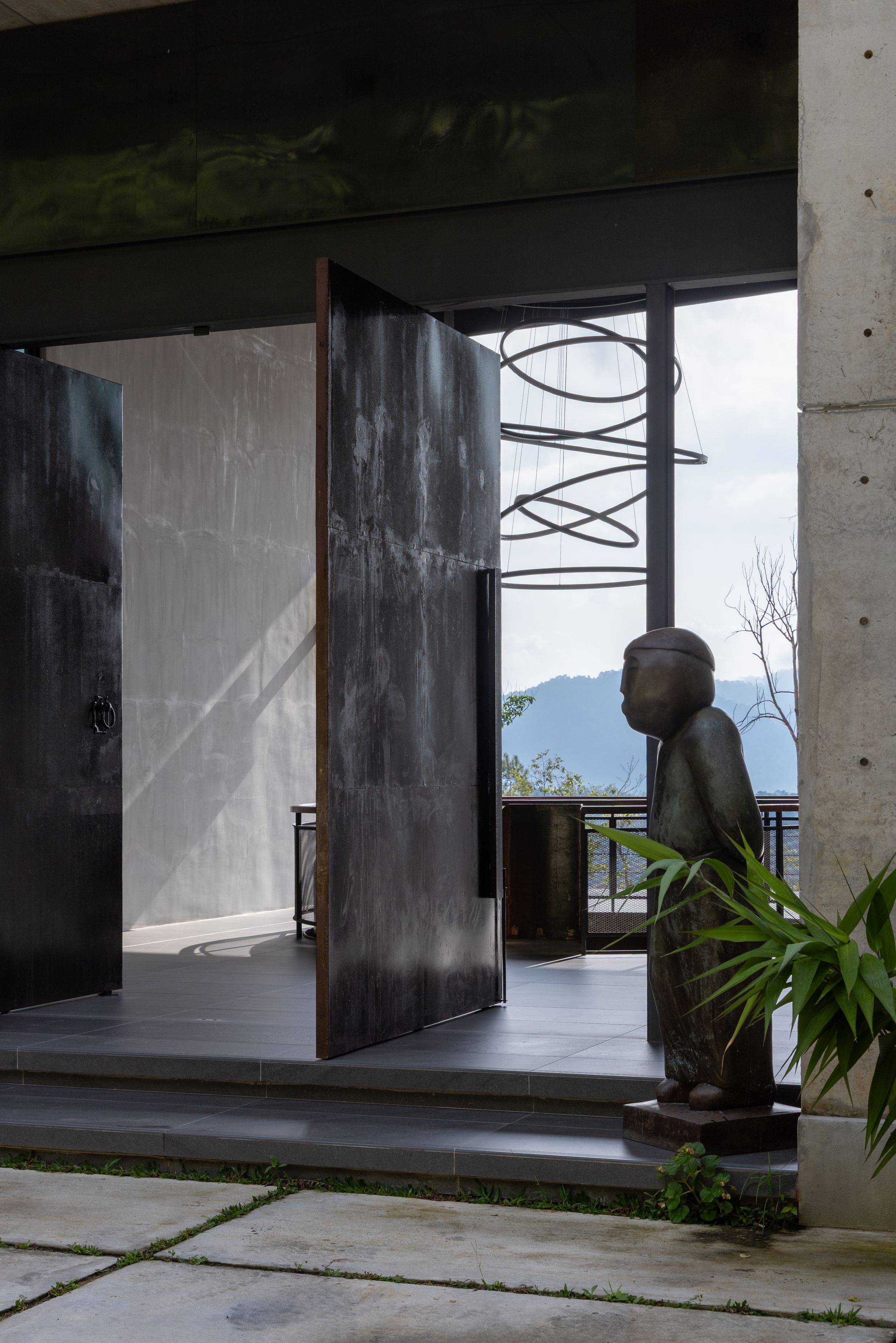 Entry courtyard at SereneNest with raw concrete walls, a stone sculpture and tropical plants