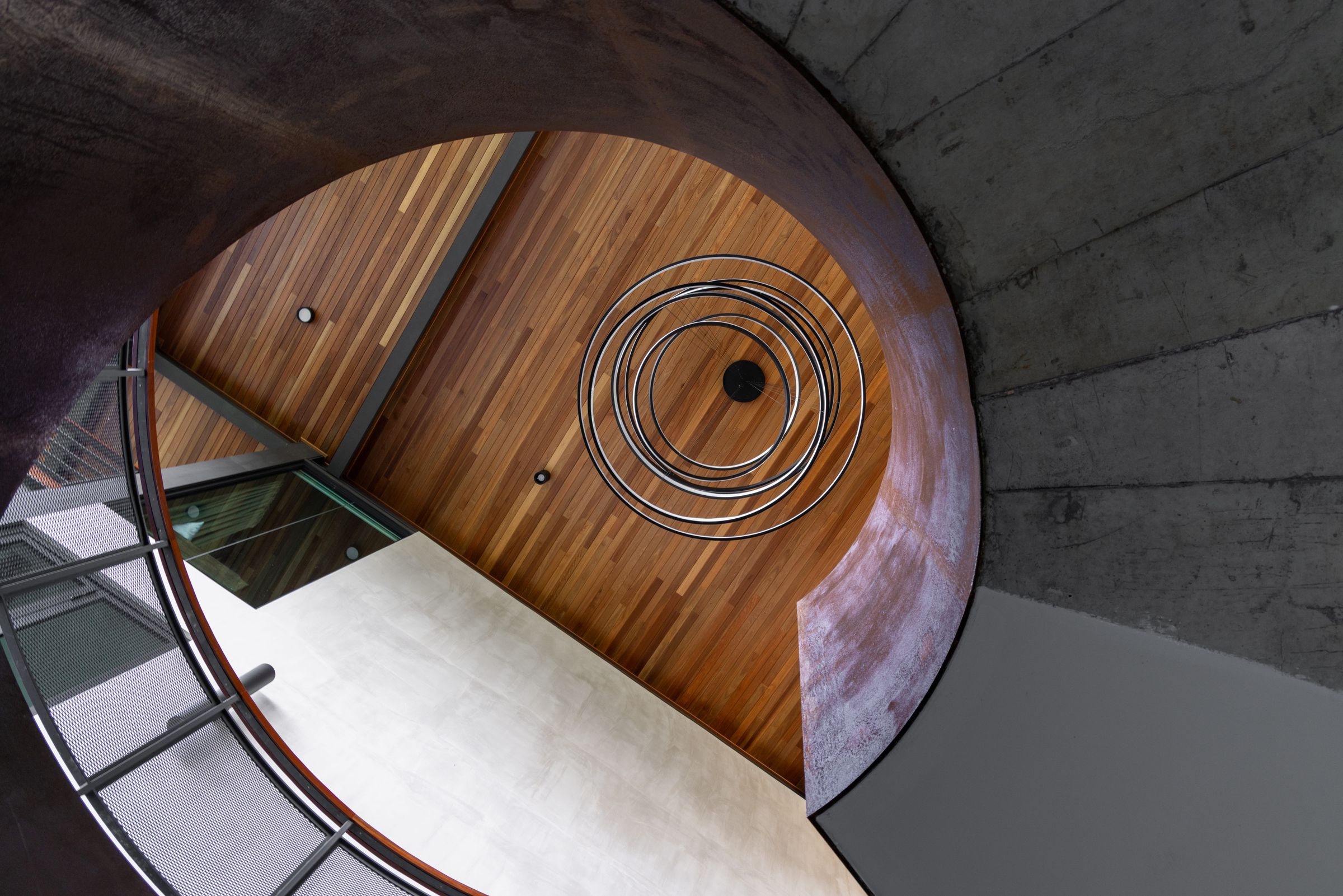 Top-down view of the timber spiral staircase at SereneNest with concrete surrounds