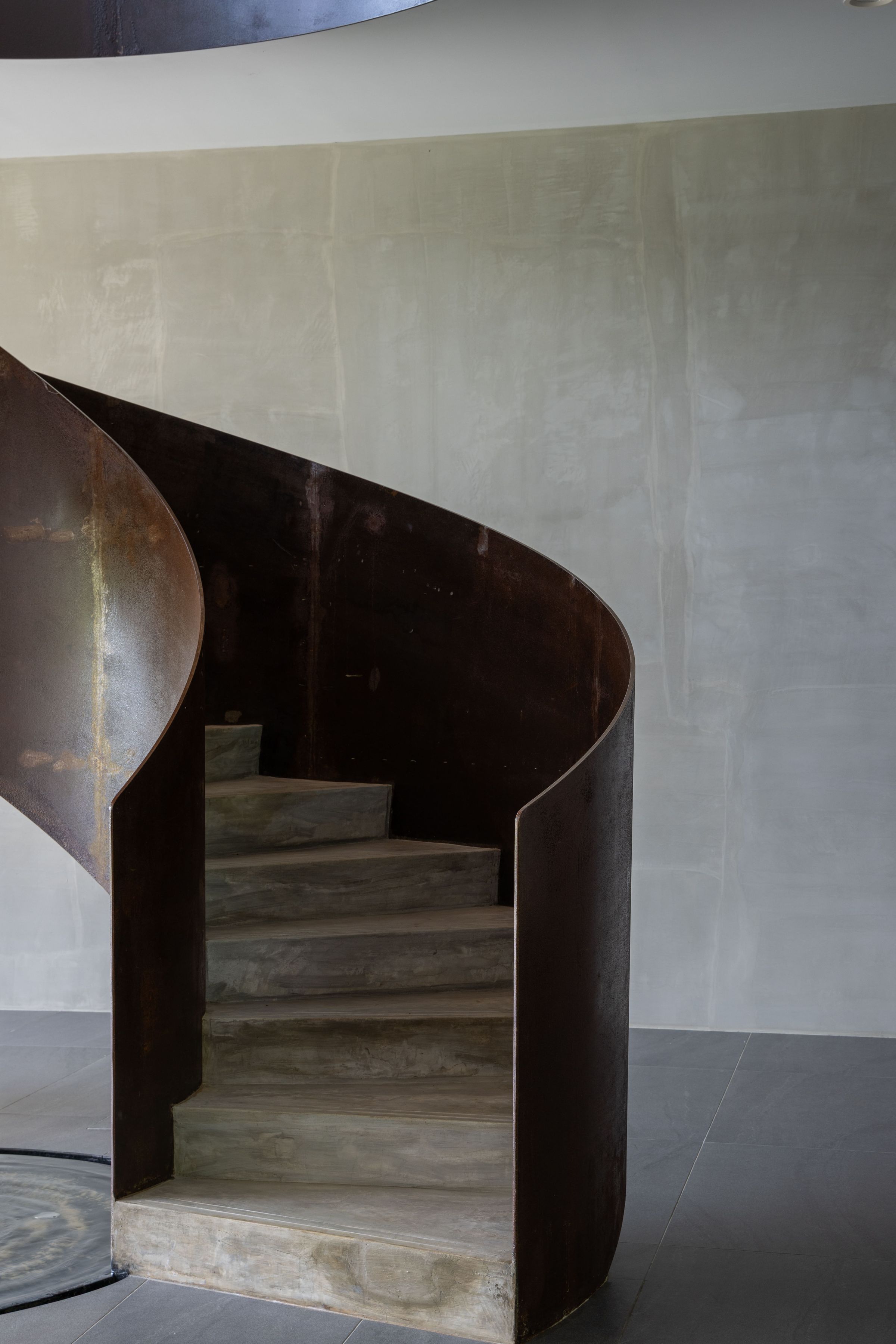Curved timber spiral staircase at SereneNest seen from below in soft daylight