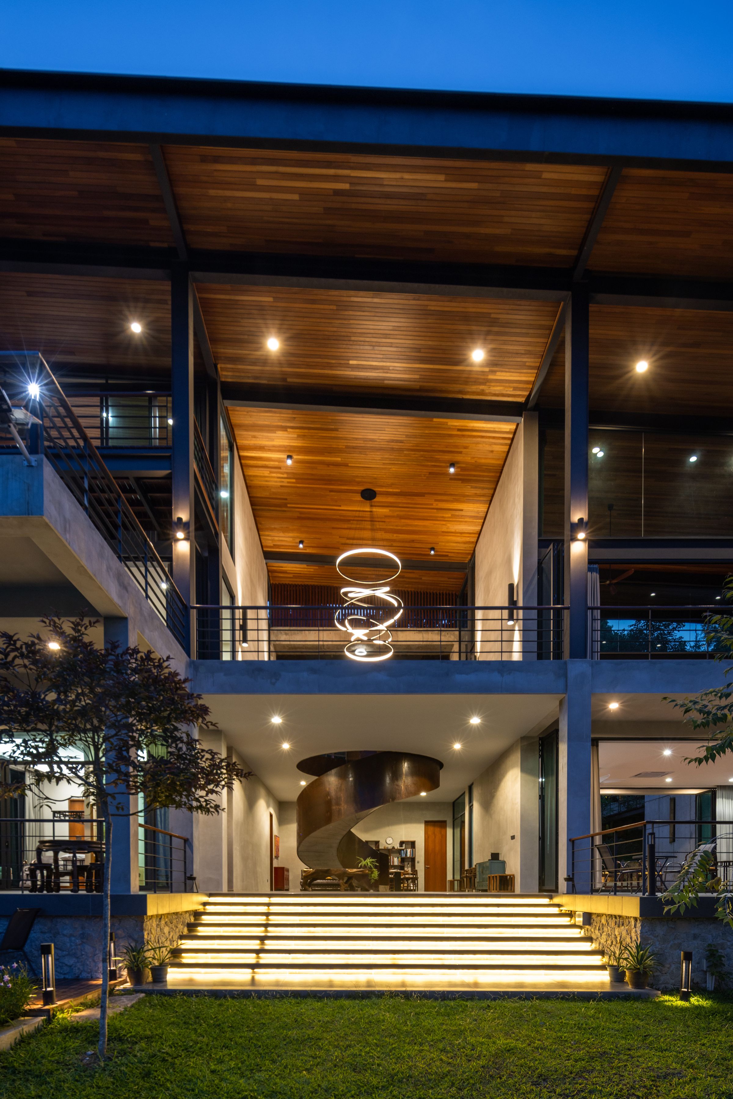 Front facade of the SereneNest villa at dusk with warm interior glow and lit steps