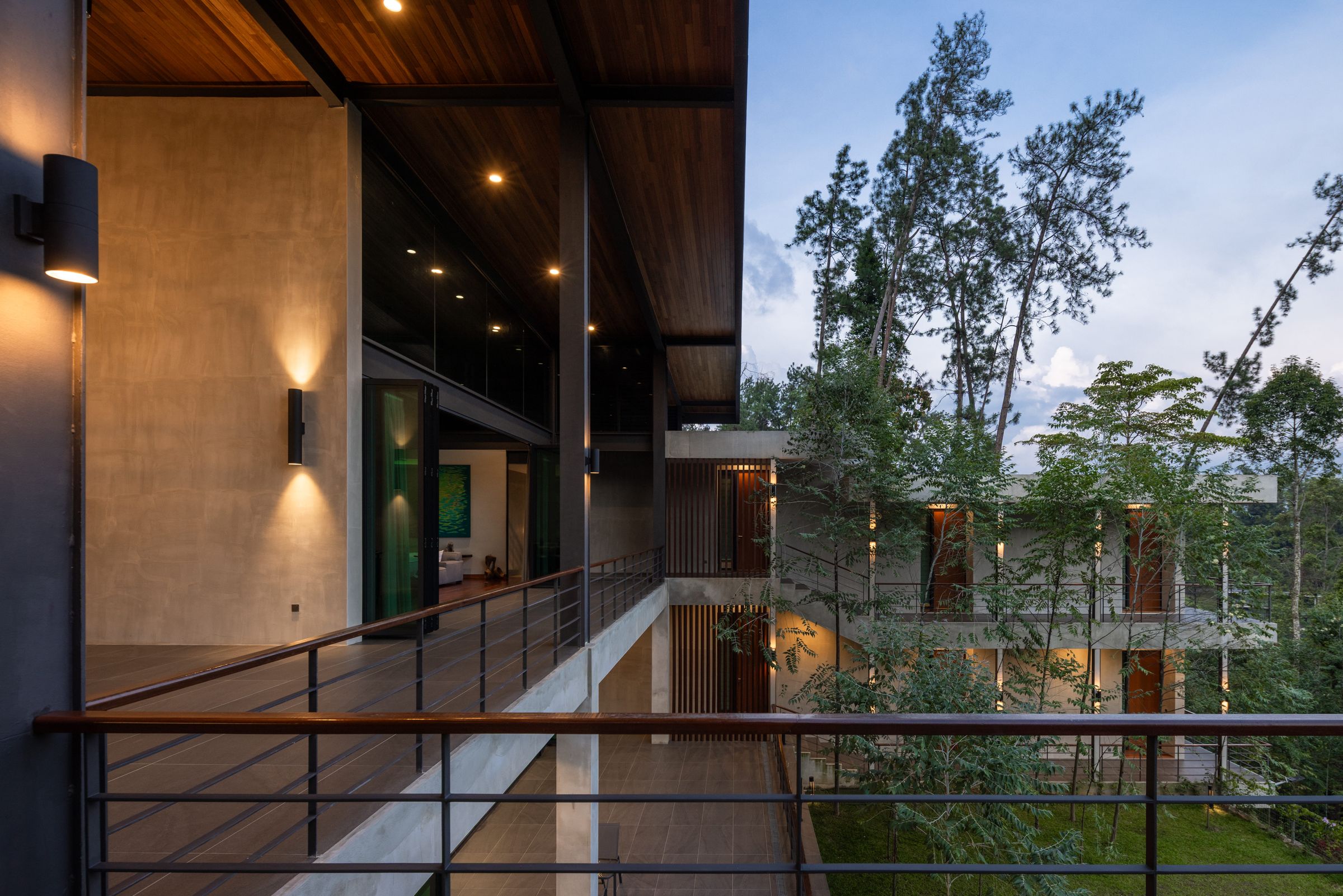 Open walkway at SereneNest between concrete walls and rainforest, with a lawn alongside