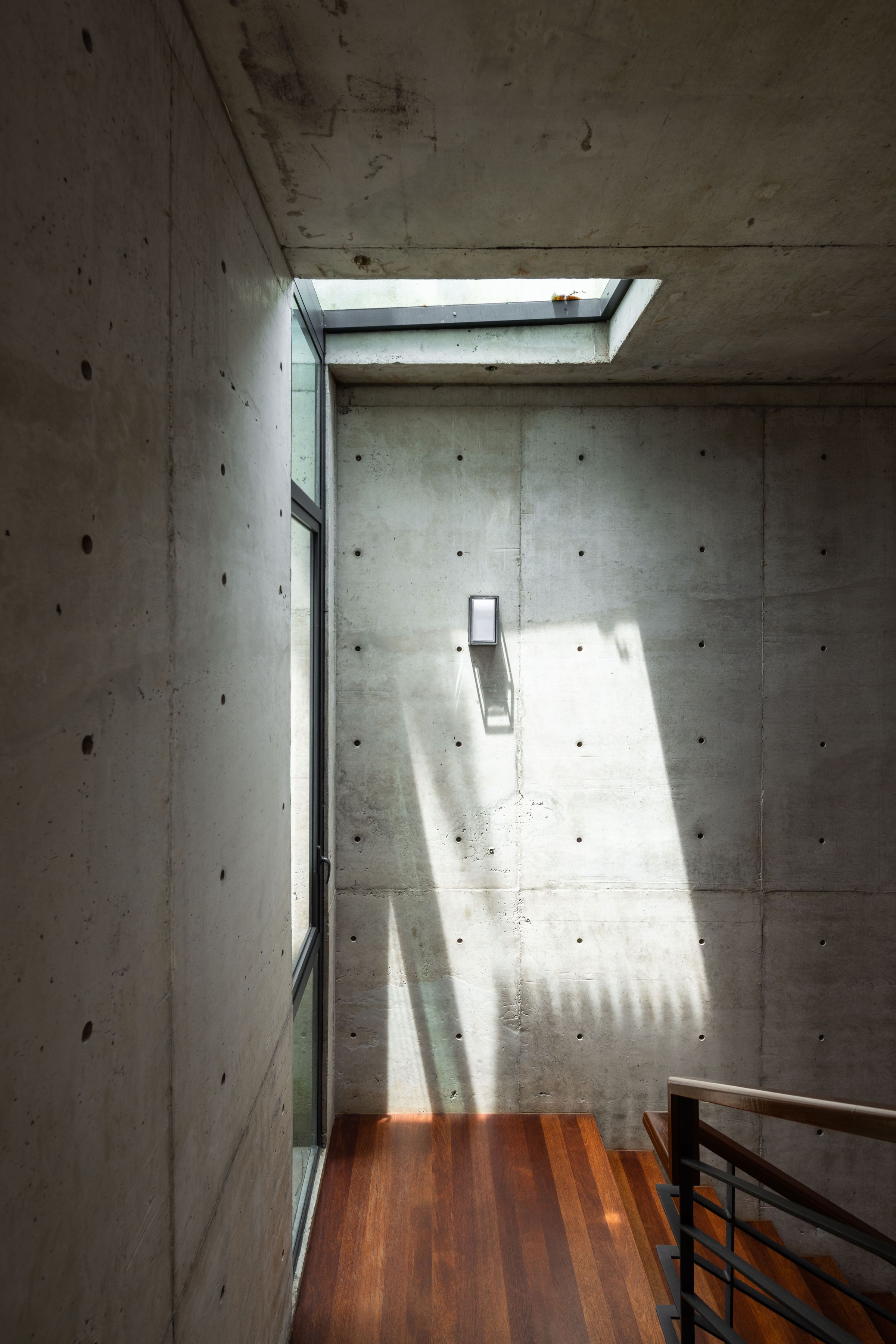 Tall concrete entry hall at SereneNest with a single shaft of natural light
