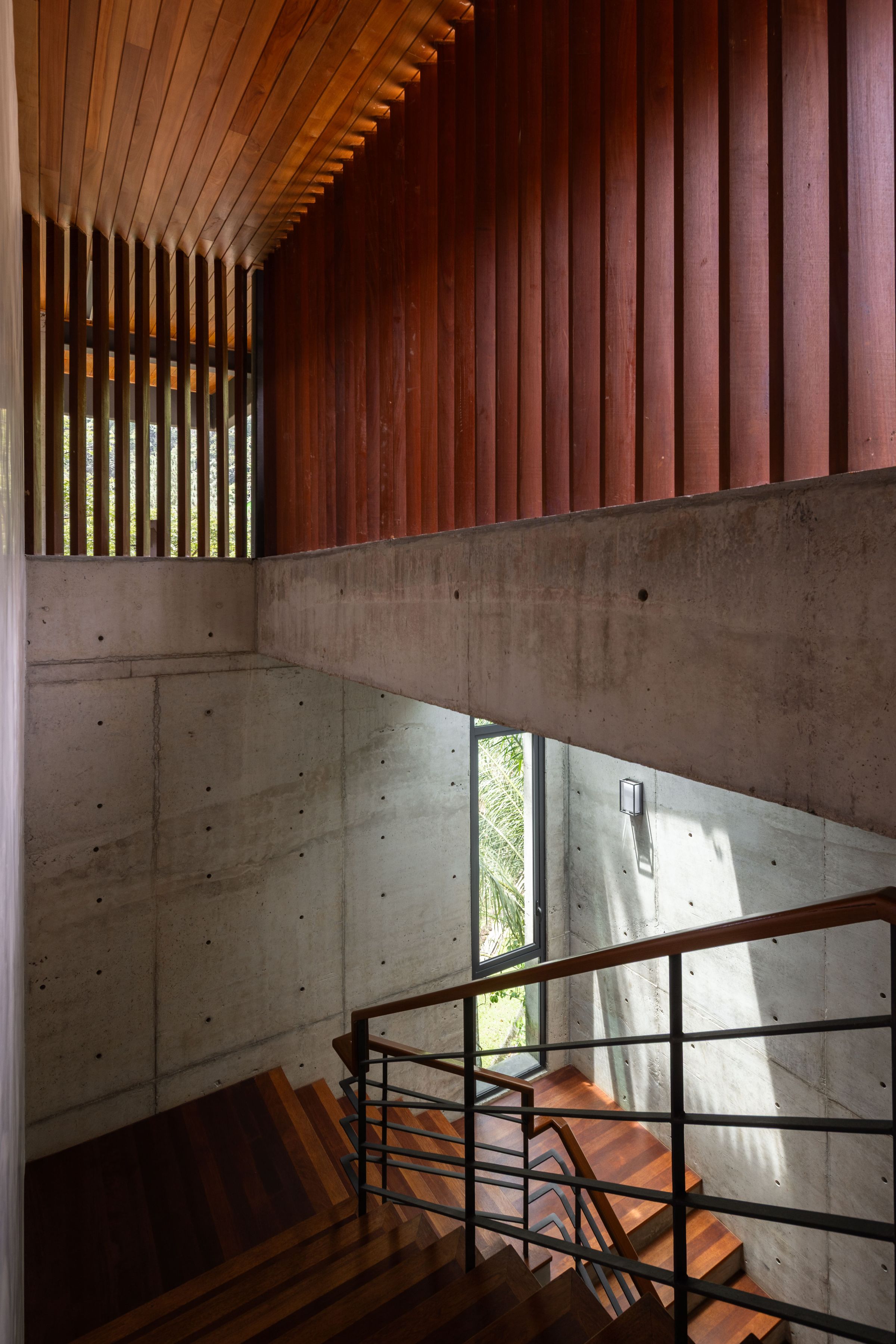 Concrete stairwell at SereneNest with timber slatted screen and a forest view beyond
