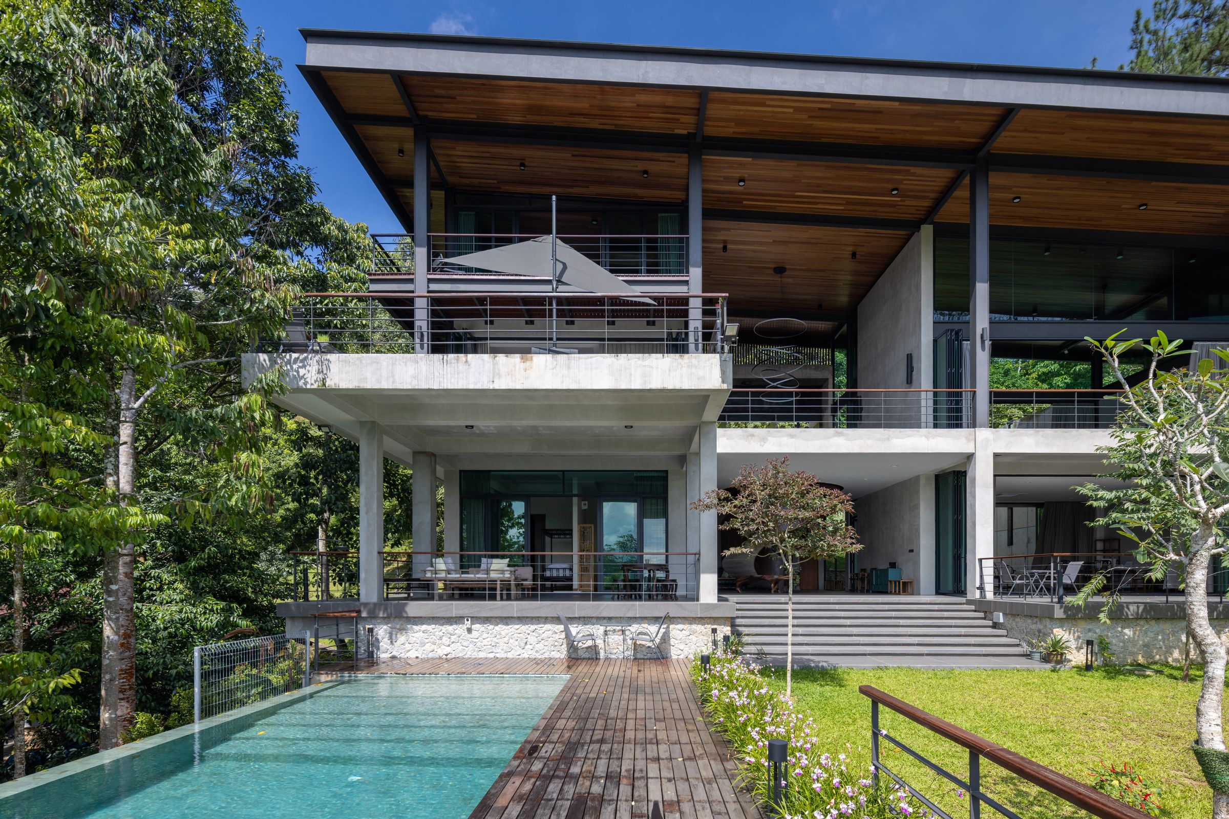 Front view of the SereneNest villa with infinity pool, deck and dense rainforest backdrop