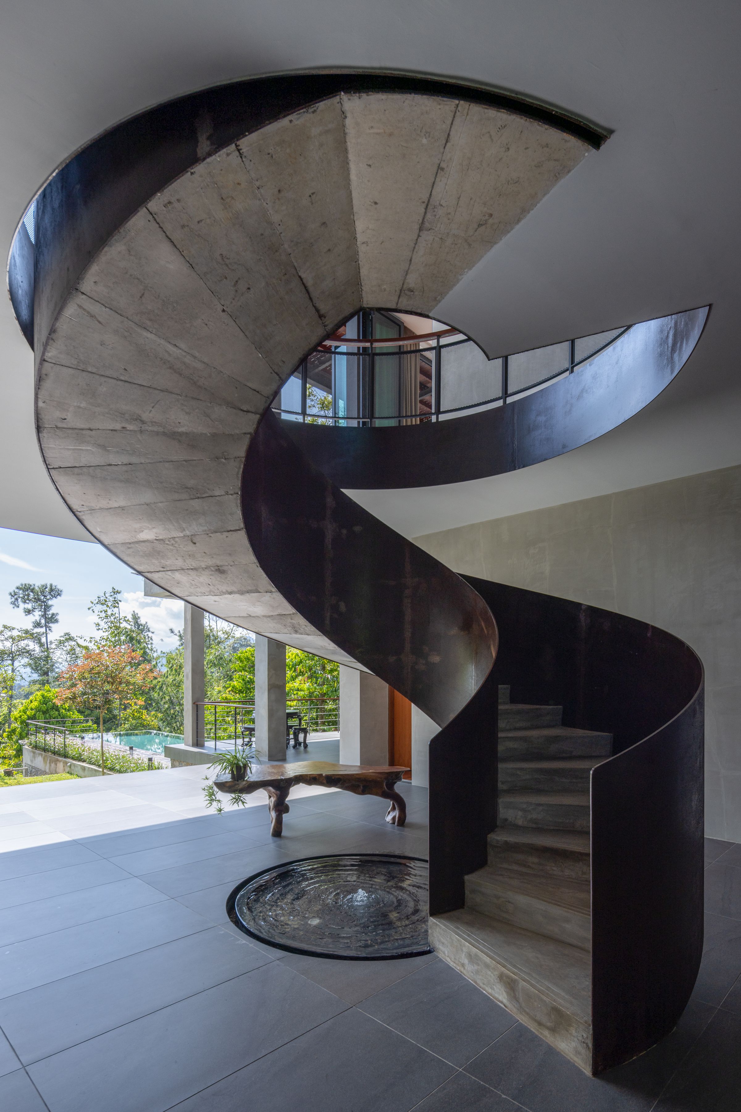 Sculptural concrete and timber spiral staircase at SereneNest seen from the side