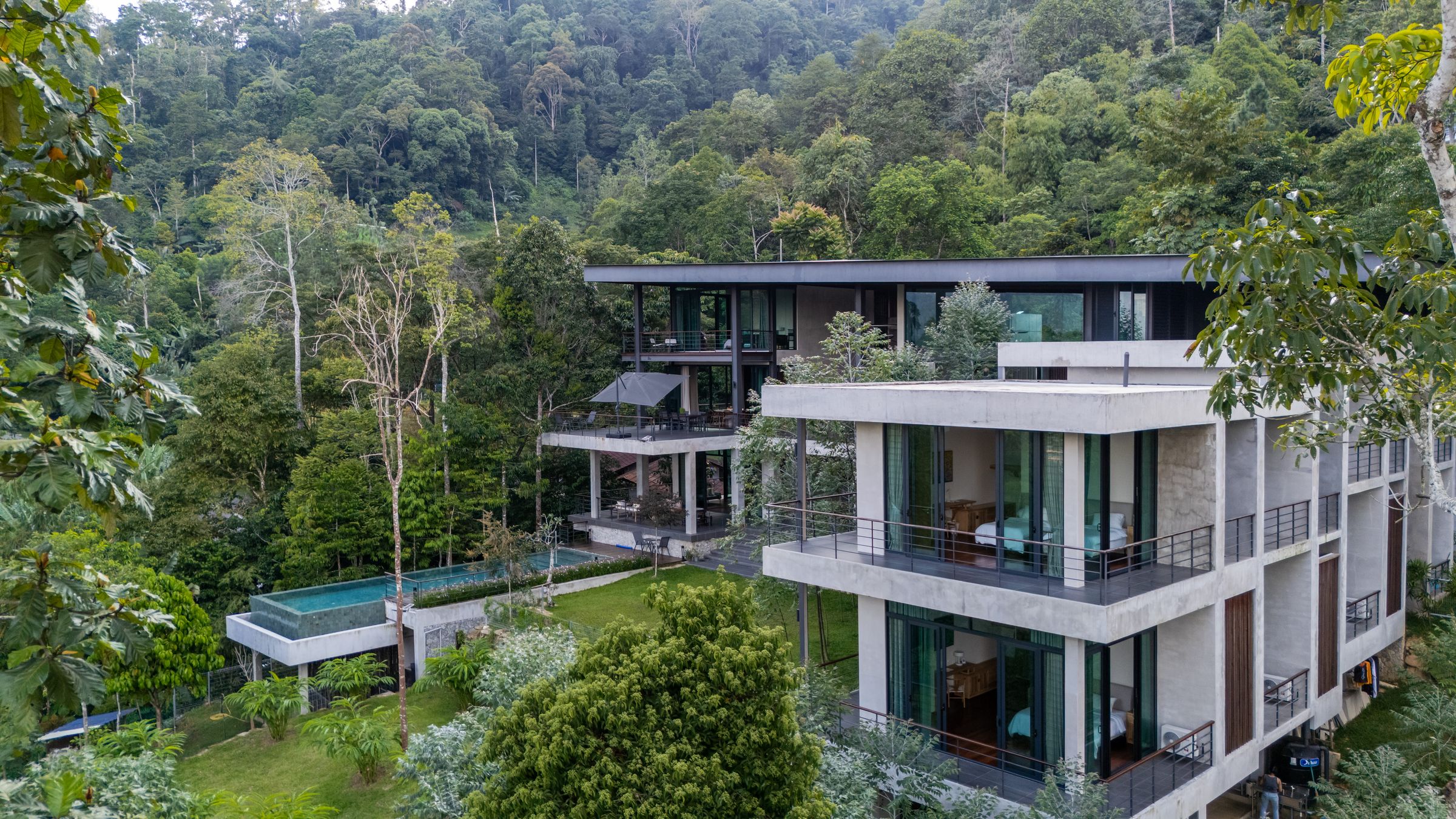 Hillside view of the multi-level SereneNest villa with a small pool tucked into the forest