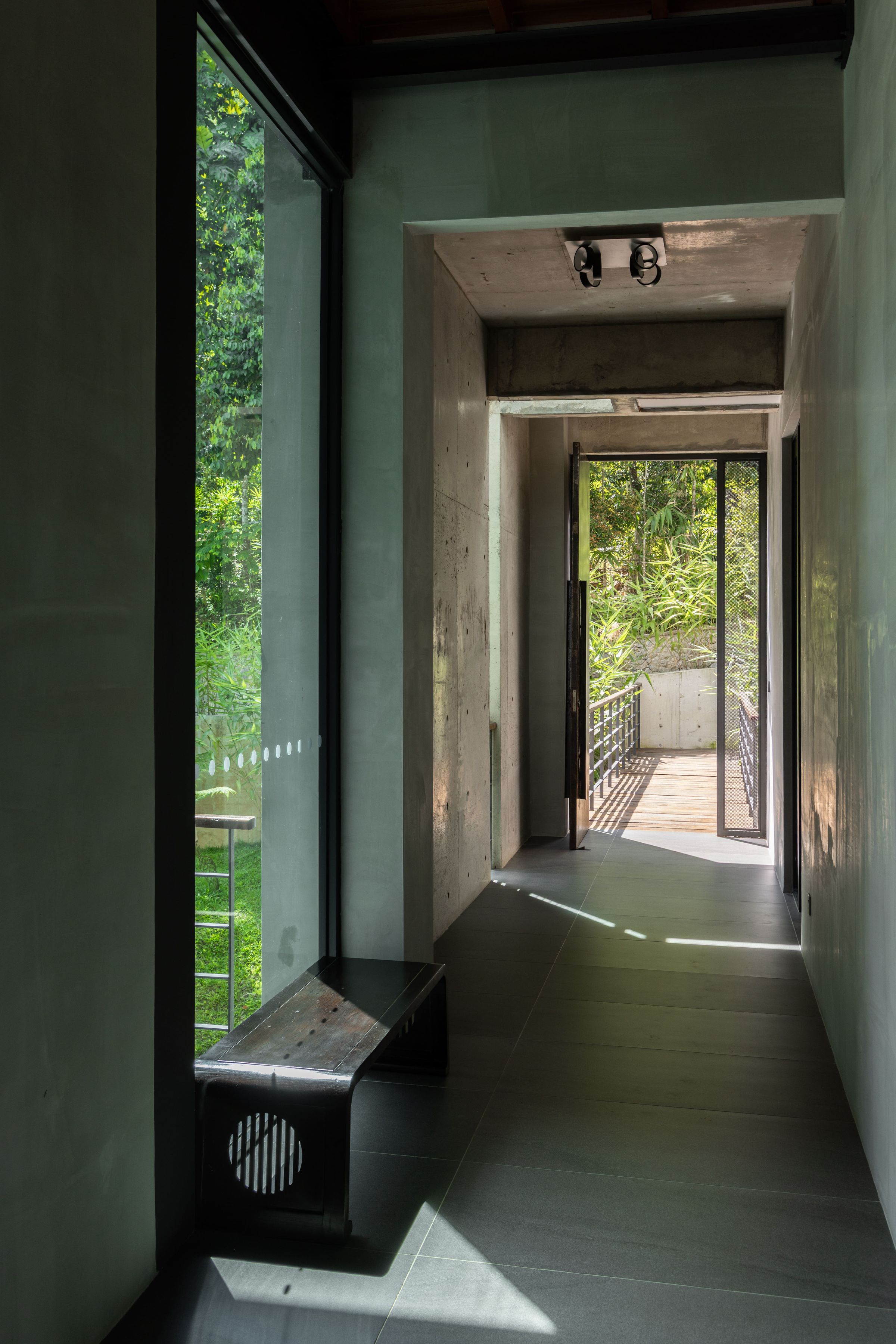 Long interior corridor at SereneNest with dark walls leading to a bright garden view