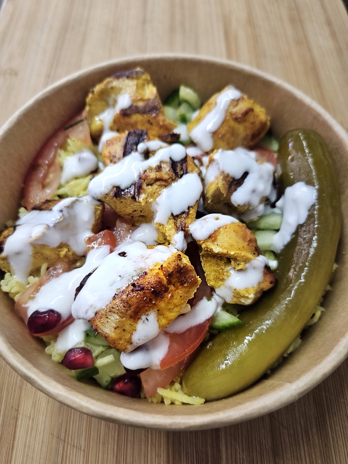 served over yellow rice with dill pickles, tomatoes, cucumbers, fresh pomegranate seeds, and garlic sauce.