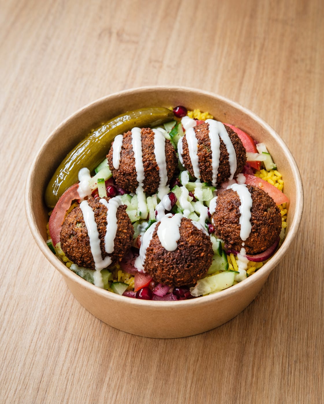 served over yellow rice with dill pickles, tomatoes, cucumbers, sumac onions, fresh pomegranate seeds, and tahini sauce.