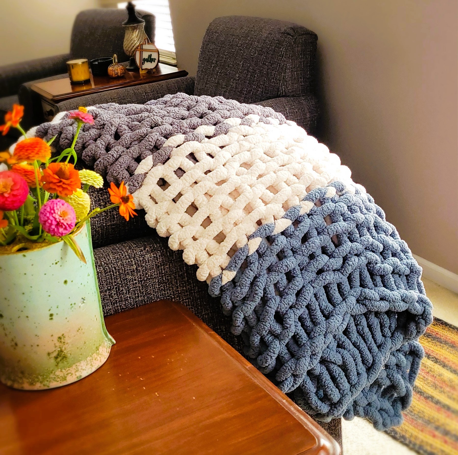 Three-tone throw (gray, ivory, and blue): Hand-knit with medium loops, giving it a cozy balance of softness and structure.